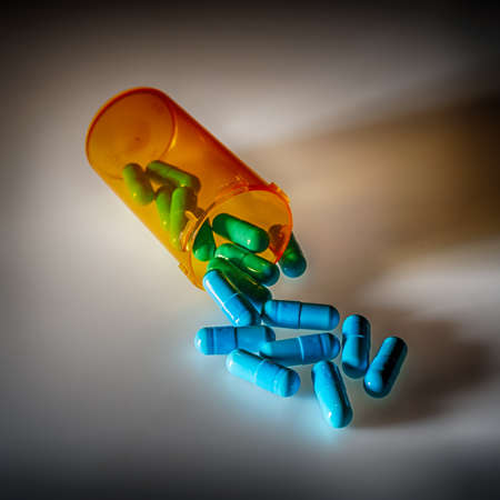 Antibiotic pills spilling out of orange pharmaceutical bottleの写真素材