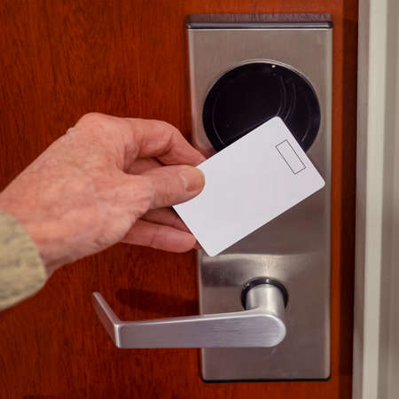 hand swiping key card to open hotel room door. Holding magnetic card for door access control swiping key card to lock and unlock doorの写真素材