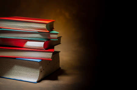 Stack of hardcover books on brown background, space for text on the rightの写真素材