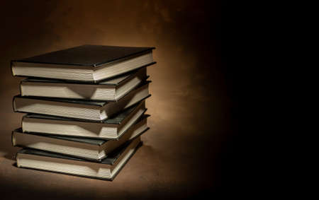 Stack of hardcover books on brown background, space for text on the rightの写真素材