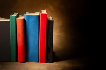 Stack of hardcover books on brown background, space for text on the rightの写真素材