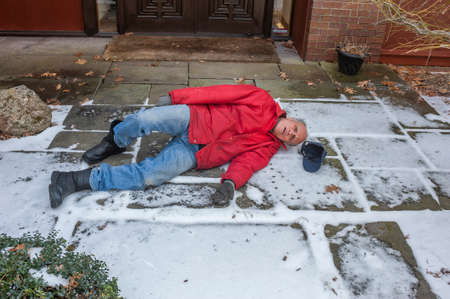 Senior man slipped on ice coming out of his houseの写真素材