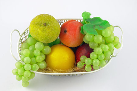 wire basket filled with various fruits on a white backgroundの写真素材