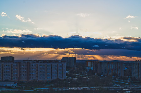 Sunset over the city. The rays of the sun break through the clouds.の写真素材