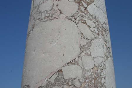 Part of an old column with cracks on a background of sky