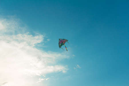Colorful kite flying in blue sky selective focusの写真素材