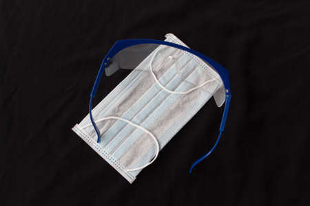 Close up shot of medical accessories on warm background. Plastic glasses and face mask supply during...