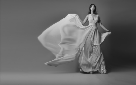 Young model posing in elegant long dress fluttering in the windの写真素材