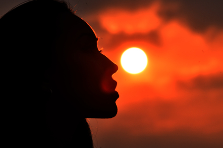 Silhouette of female face on sunset background.の写真素材