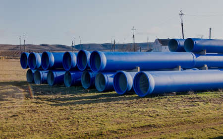 large diameter blue concrete pipes lie in the field. close-up