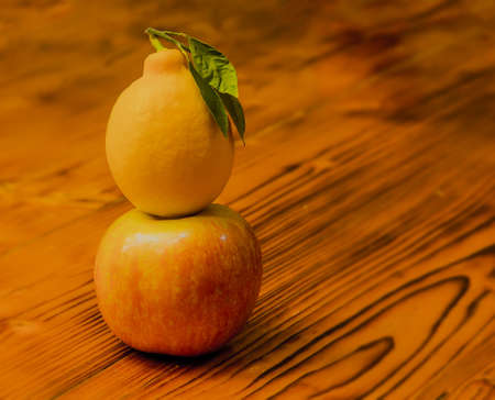 Yellow juicy lemon on a ripe beautiful apple. against the background of aged woodの写真素材