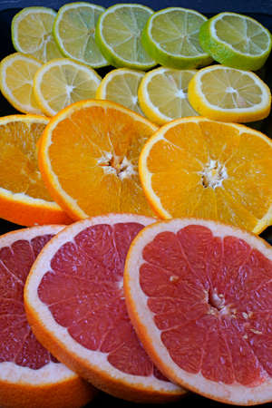 Citrus fruit sliced and arranged on black serving platterの写真素材
