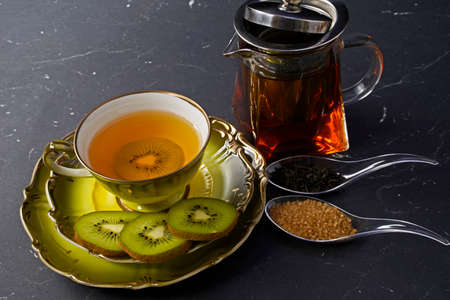 black tea with kiwi in a cup, teapot, kiwi in slicesの写真素材