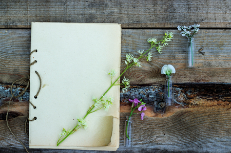 handmade sketchbook with old pen and small bouquet of wildflowers on a wooden backgroundの写真素材