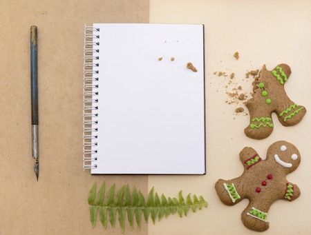 Mock up decorated Christmas gingerbread biscuits and blank notepad with craft paper backgroundの写真素材