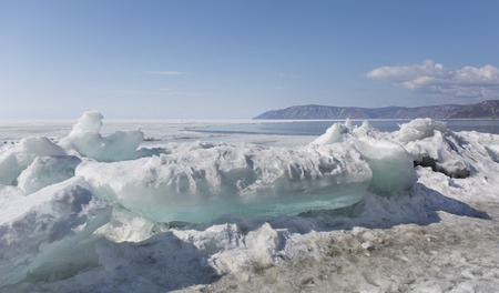 Transparent blue ice hummocks on lake Baikal shore. Siberia winter landscape view. Snow-covered ice of the lake. Big cracks in the ice floe.の写真素材