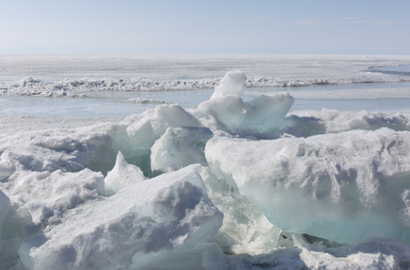 Transparent blue ice hummocks on lake Baikal shore. Siberia winter landscape view. Snow-covered ice of the lake. Big cracks in the ice floe.の写真素材