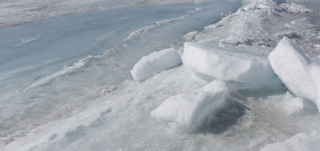 Transparent blue ice hummocks on lake Baikal shore. Siberia winter landscape view. Snow-covered ice of the lake. Big cracks in the ice floe.の写真素材