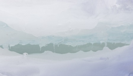 Transparent blue ice hummocks on lake Baikal shore. Siberia winter landscape view. Snow-covered ice of the lake. Big cracks in the ice floeの写真素材