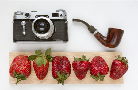 Mock up for artwork with old camera, red strawberries and smoking pipe. Top view. Place for textの写真素材