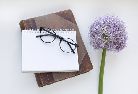 Notebook mock up for artwork with purple allium and glasses. Top view. Place for text. Fresh flower.