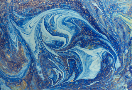Marbled blue abstract background with golden sequins. Liquid marble ink pattern.の写真素材
