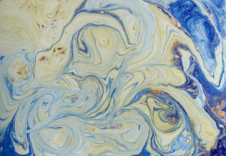 Marbled blue abstract background with golden sequins. Liquid marble ink pattern.の写真素材