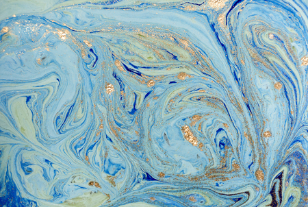 Marbled blue abstract background with golden sequins. Liquid marble ink pattern.の写真素材