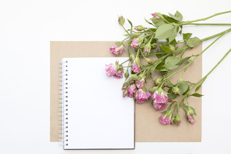 Mockup with blank notepad and little garden pink roses. Workspace.の写真素材