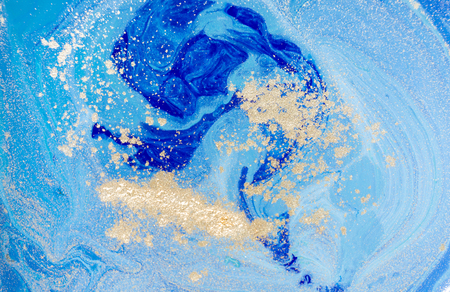 Marbled blue abstract background with golden sequins. Liquid marble ink pattern.の写真素材