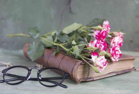 Vintage notebook mock up for artwork with pink roses. Place for text. Fresh flowers and black glassesの写真素材