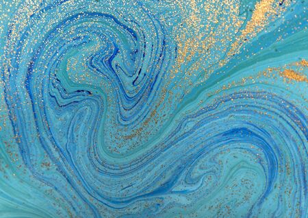 Marbled blue abstract background with golden sequins. Liquid marble ink pattern.の写真素材