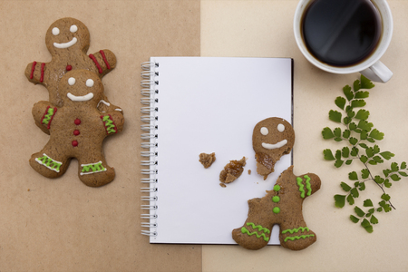 Ginger bread cookies on craft paper background . Blank notepad with leaf of fern. Coffee Christmas mockup. Top view.の写真素材