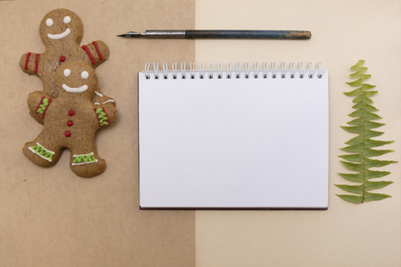 Ginger bread cookies on craft background. Blank notepad with leaf of fern. Christmas mockup. Top view.の写真素材