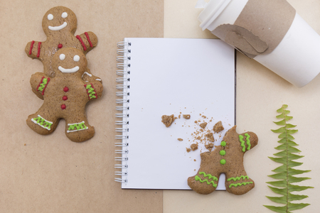 Ginger bread cookies on craft background. Blank notepad with leaf of fern. Coffee mockup. Top view.の写真素材