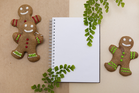 Ginger bread cookies on craft background. Blank notepad with leaf of fern. Christmas mockup. Top view.の写真素材