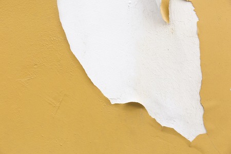 Grunge wall with peeling yellow paint texture.の写真素材