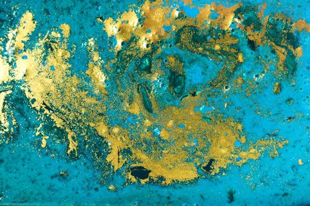 Liquid uneven blue and green marbling pattern with golden glitter and glare of lightの写真素材