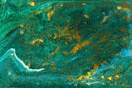Liquid uneven green marbling pattern with golden glitter and glare of lightの写真素材