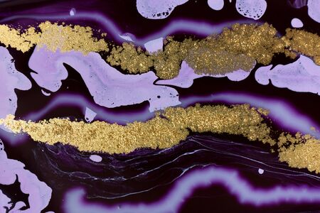 Mixed purple inks background with golden glitter. Abstract paint texture.