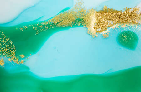Piles of gold sequins on green and blue smudges of paint. Abstract pattern.の写真素材