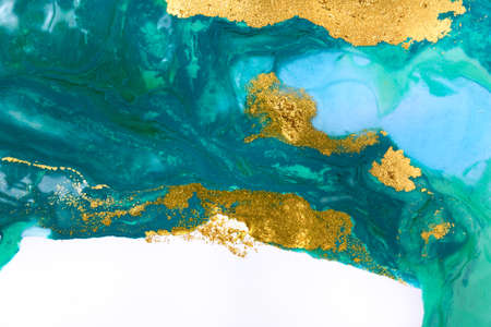 Gold and blue mixed inks splattered on white paper background.