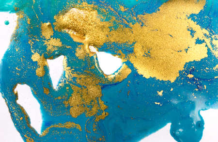 Gold and blue mixed inks splattered on white paper background.