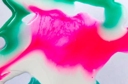 Pink, white and green mixed inks spilled on white paper background with copyspace
