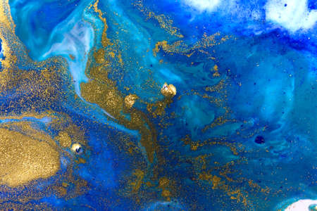 Blue and gold sequins on white paper background.の写真素材