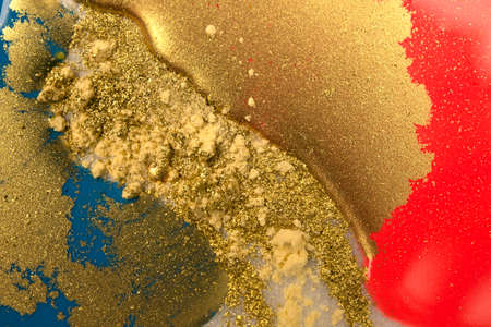 Piles of gold sequins on pink smudges of paint. Abstract pattern.の写真素材