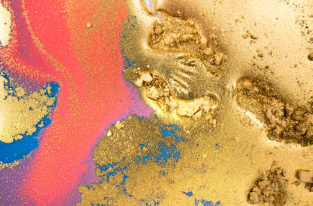 Piles of gold sequins on pink smudges of paint. Abstract pattern.の写真素材