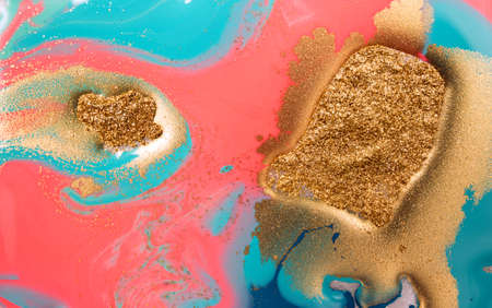 Piles of gold sequins on pink smudges of paint. Abstract pattern.