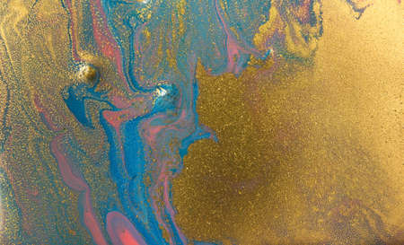 Piles of gold sequins on pink and blue smudges of paint. Abstract pattern.