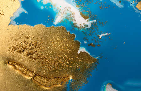 Piles of gold sequins on blue smudges of paint. Abstract pattern.の写真素材
